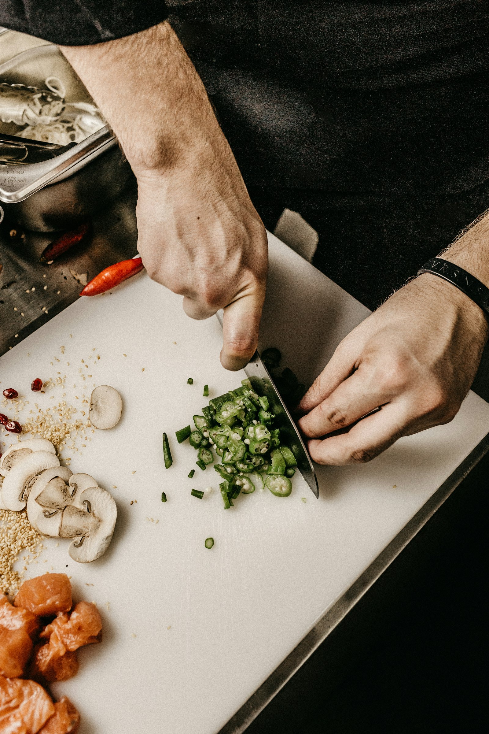 Le mani di un cuoco affettano gli ingredienti sul banco da lavoro