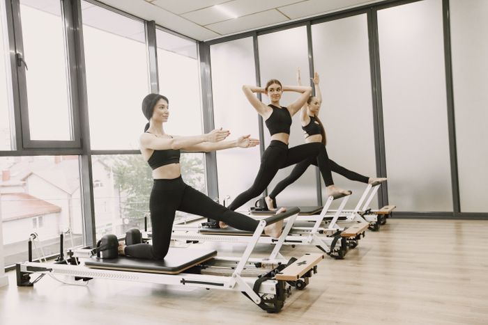 Lezione di Pilates di gruppo su reformer con istruttrice