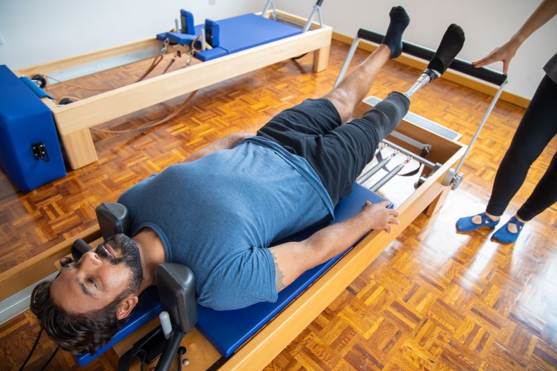 Donna che pratica Pilates su reformer in uno studio luminoso